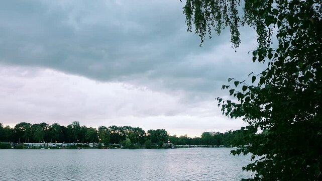 Serene lake with overcast sky and lush trees on the shore  