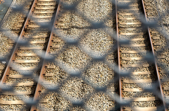 Parallel railway tracks with fence shadows