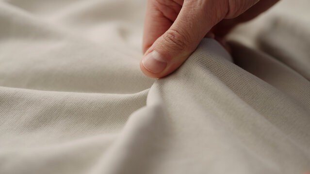 man manually check ivory color cotton fabric for clothing with hands