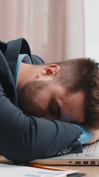 Bored sleepy Caucasian businessman worker working on laptop computer, leaning on hand falling asleep at home office. Exhausted tired freelancer workaholic young man. Employment, occupation, workless