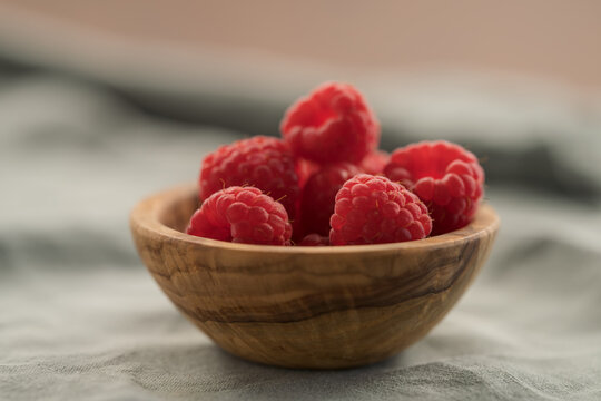 fresh ripe raspberries in a small wooden bowl