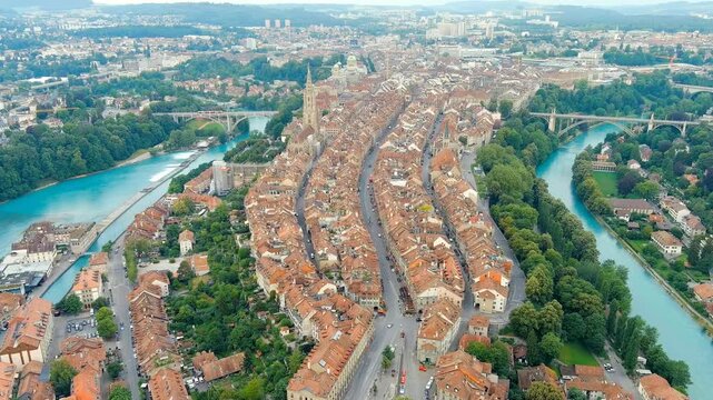 Bern, Switzerland. The Zytglogge clock tower rising above the UNESCO-listed Old City, panoramic Drone footage over terracotta rooftops and the turquoise Aare River on a summer morning. Drone footage