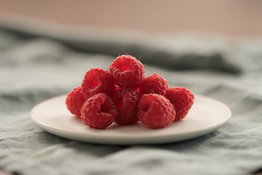 fresh ripe raspberries on a white saucer
