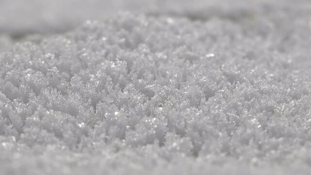 Hoarfrost crystals cover a frozen surface, forming delicate winter patterns in white ice. Rime texture creates an abstract icy background with intricate geometry and subzero detail.