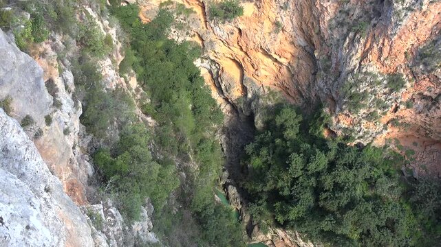 Antalya Guver Canyon aerial drone view shows deep rocky gorge cliffs, karst cave, rugged valley. Birds eye scene reveals ravine escarpment, chasm limestone formation, natural fissure landscape.