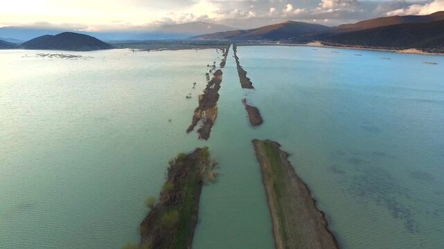 Aerial drone view shows floodwaters submerging roads homes and settlements across wide region. High angle disaster scene reveals drowned infrastructure inundated land catastrophic deluge.