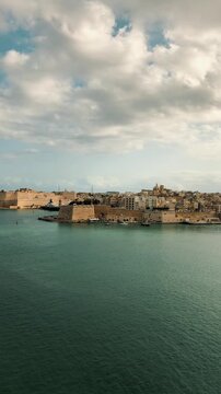  A breathtaking panoramic view of the Grand Harbour in Valletta, Malta, showcasing historic coastal fortifications maritime shipyards, docking cruise vessels, defensive artillery cannons on a suny day