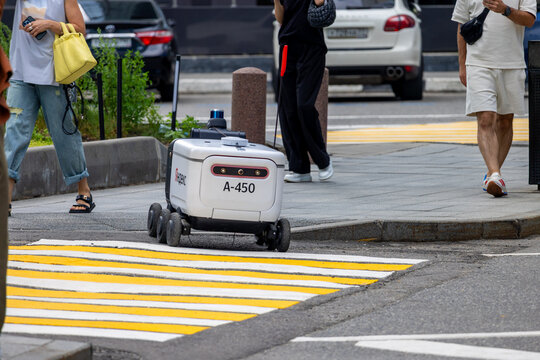 Yandex delivery robot on a city street among pedestrians, autonomous rover delivering or carrying goods. Moscow, Russia - July 20, 2024