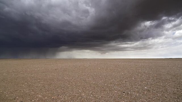 Gobi Desert in Mongolia lies beneath storm clouds across barren treeless plains. Arid flatlands show dry terrain, rare weather tension and remote desert wilderness.