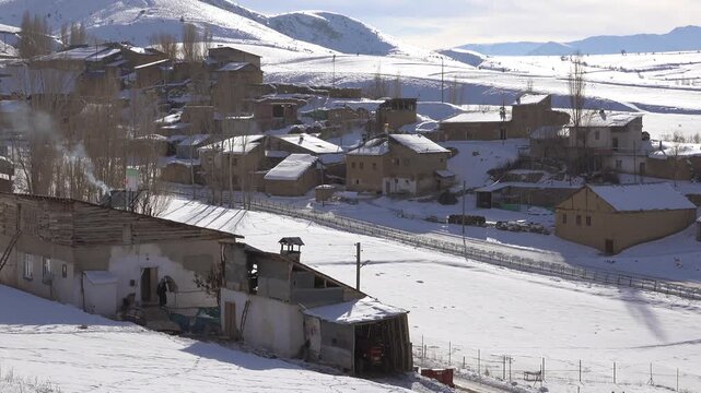 Snow covered Tajikistan village showing traditional houses and quiet countryside. Frozen homes rest within cold highlands, seasonal stillness, mountain climate visual appeal.