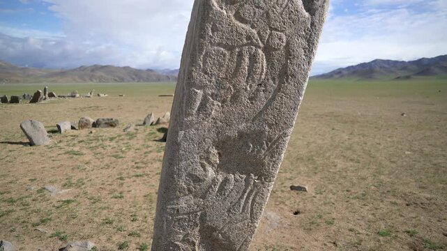 Central Asian deer stone megalith carved with ancient symbols standing on open steppe. Prehistoric stele records nomadic belief, funerary custom, archaeological value, early Eurasian heritage.