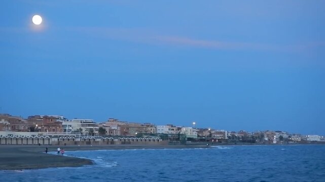 Full moon in October called Hunter&rsquo;s Moon and sky with clouds over horizon of coast of Tyrrhenian Sea with blue water in Rome Ostia in Italy. Topics: astronomy, Europe, city, travel, evening, sea view