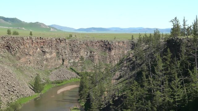 River flows along a deeply incised rocky valley shaped by long term fluvial erosion. Geomorphic landforms display sediment movement, ravine walls, watercut slopes, terrain evolution.