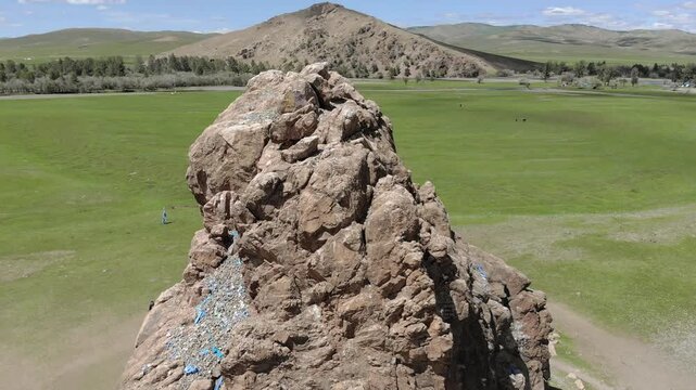 Aerial view of Taikhar Rock rising from flat grassland plain sacred tourism landmark in Mongolia. Granite monolith marks ritual heritage, pilgrimage appeal, steppe symbolism, cultural destination.
