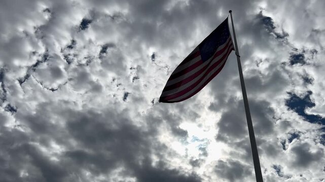  american flag in shadow blowing against overcast sky