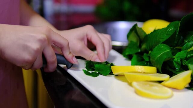 Fresh citrus is carefully cut into thin slices while aromatic mint waits nearby for refreshing recipes. Bright ingredients are prepared for homemade drinks and desserts.