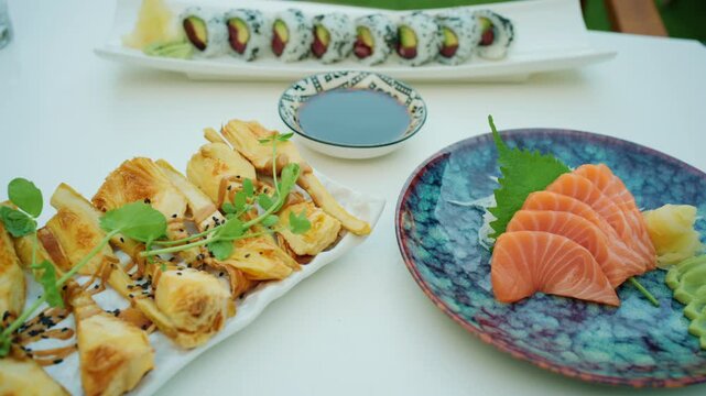 Close-up of sliced salmon sashimi with a shiso leaf, wasabi and pickled ginger on a decorative plate