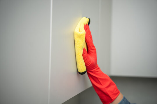 Washes the cabinet with a glove and a rag