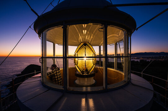 Lighthouse keeper beside Cabo Mayor lighthouse lantern at sunrise in Santander, Spain