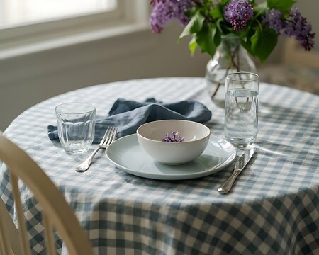 Cozy rustic dining table set with checkered tablecloth and fresh lilac flowers in a vase