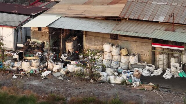Large storage area with stacked white sacks near an industrial building during the daytime