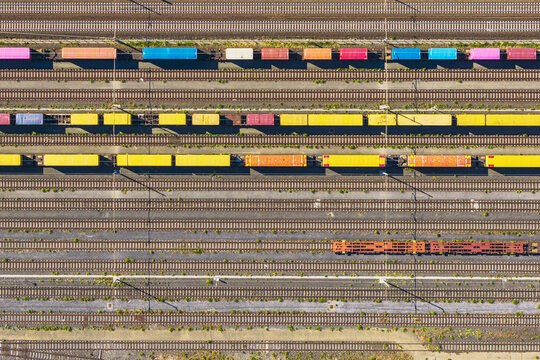 Aerial view of colorful freight train cars lined up on parallel railway tracks in the industrial rail yard of La Spezia, Liguria, Italy.