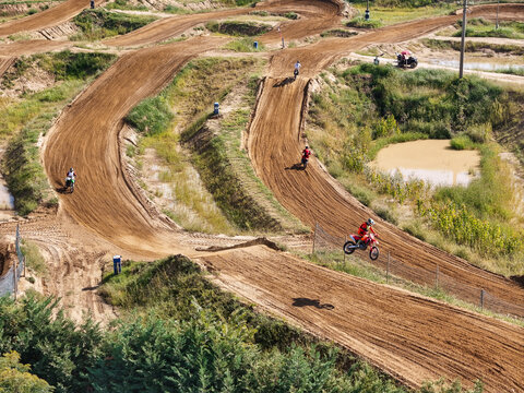 Aerial view of motocross riders racing on the dirt track at Dornoland with jumps, berms, and muddy terrain in Dorno, Lombardia, Italy.