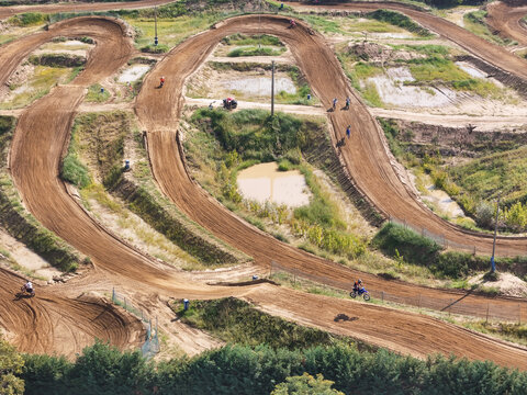 Aerial view of Dornoland motocross track with dirt paths, riders on motorcycles, and surrounding greenery in Dorno, Lombardia, Italy.