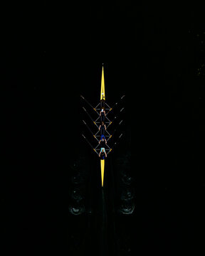 Aerial view of a yellow rowing boat with rowers gliding across dark water in Poland.