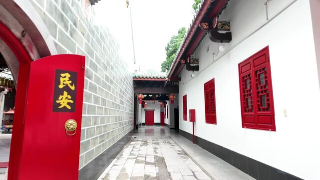 Traditional moon gate entrance and red wooden lattice doors at a historic Chinese temple in Cholon, Ho Chi Minh City, Vietnam