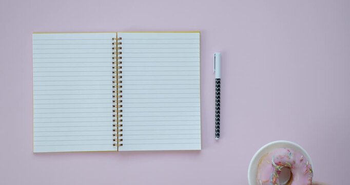 Open spiral notebook with lined pages and patterned pen on light pink surface stationery paper writing office desk