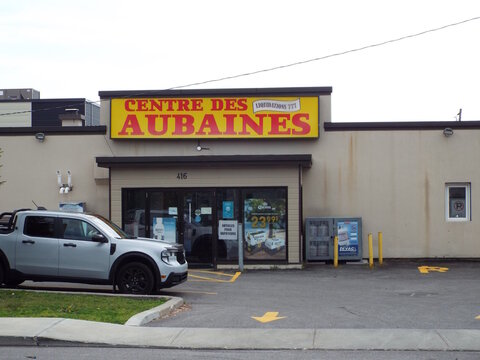 Gatineau, Quebec, Canada &ndash; July 02, 2026: A commercial storefront displays a "Centre des Aubaines" yellow sign with address 416, featuring a parked pickup truck outside at Rue Br&eacute;beuf.