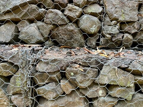Gabion retaining wall filled with natural rocks and secured with heavy wire mesh for erosion control and slope protection