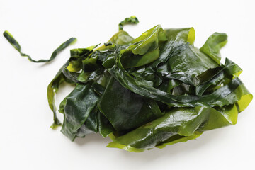 Wet wakame seaweed pile placed on white background. © Bowonpat