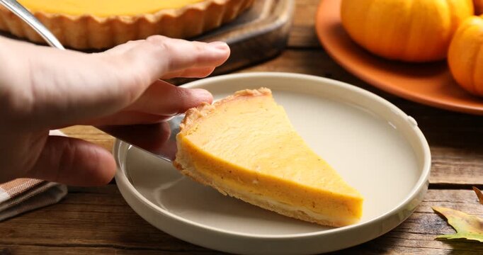 Man putting piece of delicious pumpkin pie onto plate at white table, closeup. Pastry for Thanksgiving day or other fall holiday