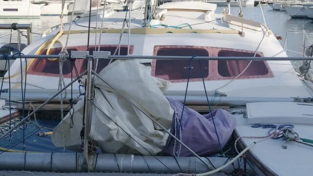 Close-up of the bow of a white sailboat with a folded sail and rigging in a marina, Cote d'Azur, France