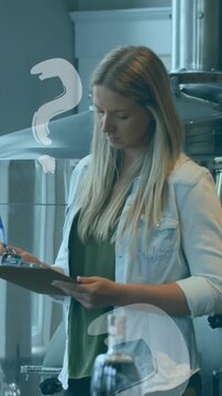 Animation of question mark symbols floating over caucasian woman writing on clipbard at the factory