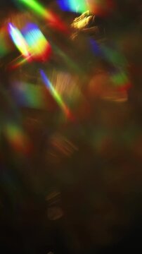Dreamy bokeh of a golden shimmer and dazzling rainbow rays. Real optical effect of shining gold creating an aura of luxury and a visual of glamorous glittering lights and sparkling reflections. Loop.