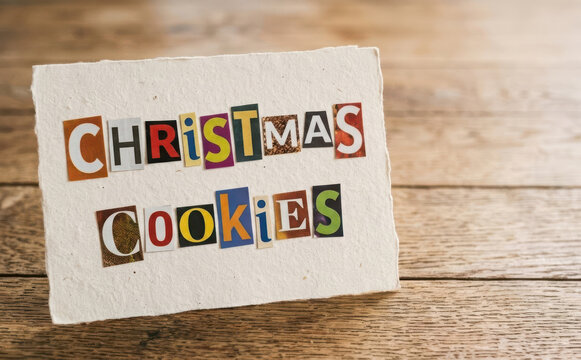 Christmas cookies text ransom note style on handmade paper card placed on wooden background for holiday baking concept