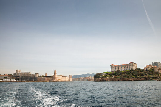 Panoramic view across Marseille waterfront toward the entrance of the Vieux Port, with Fort Saint-Jean on the left and Palais du Pharo on the right, seen from the Mediterranean in france.