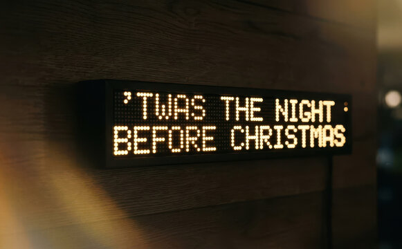 LED message board sign displaying Twas the night before Christmas poem on a wooden wall, holiday season decoration concept for winter festivities and greeting cards