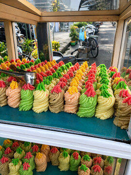 Colorful traditional Indonesian cassava cake known as Getuk Lindri displayed inside a glass street vendor cart