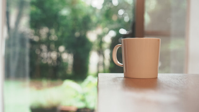 Coffee Mug on Wooden Table by Window with Greenery