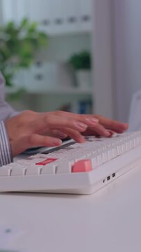 Wireless computer keyboard hand typing white desktop office desk, colorful keycaps and focused hands creating productive remote work technology atmosphere with blurred home office background Vertical