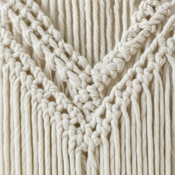 Handmade macrame wall hanging with intricate knot pattern on white wall, boho home decor lifestyle interior photography