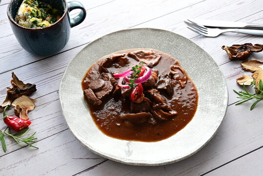 Traditional Czech cuisine featuring tender venison with mushrooms and bread dumplings served on a clean white plate.