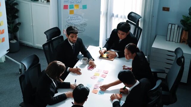 Top view of smart business team brainstorm idea by writing in sticky notes at meeting. Group of professional analysts planning marketing strategy and brainstorming in conference. Teamwork. Directorate