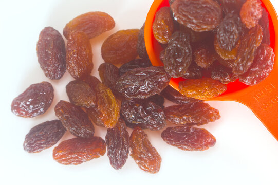 Raisins and an orange measuring spoon macro close up