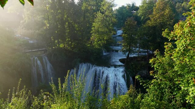 Scenic waterfall cascades down lush greenery in Rastoke Croatia at sunrise.