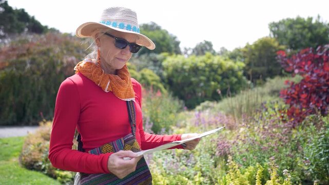 A senior woman looks at a map at the Mendocino coast Botanical Gardens in Fort Bragg, California, looking at flowers and enjoying the beauty.